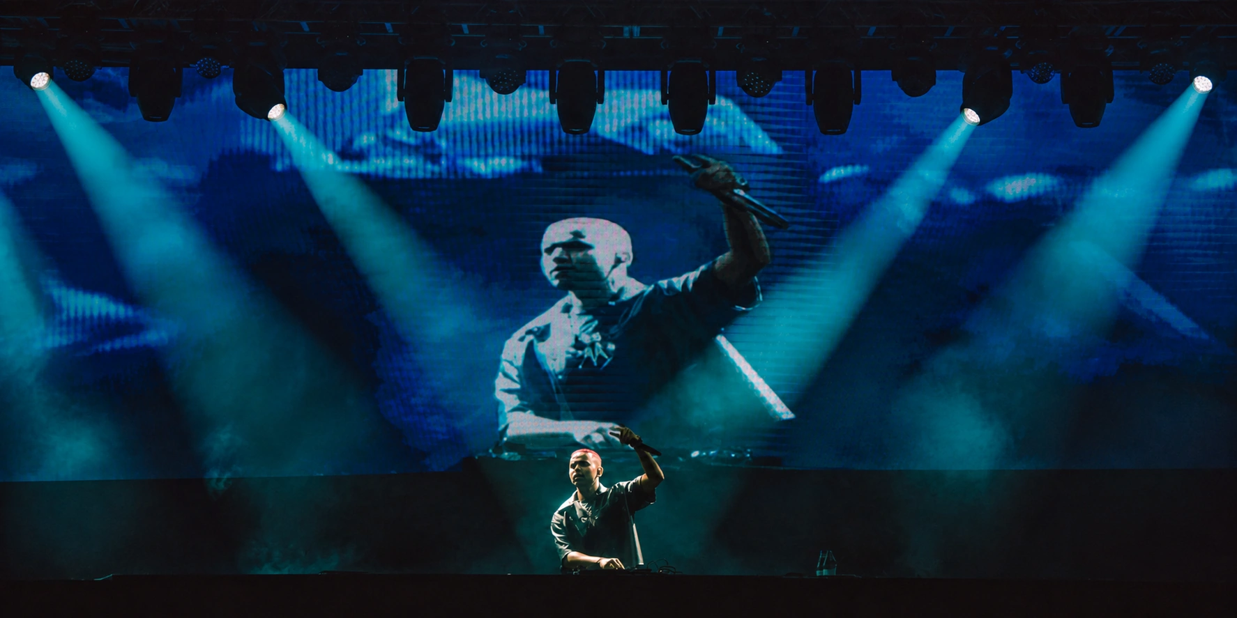 DJ Matt-D se apresentando no palco, diante de uma projeção de seu show